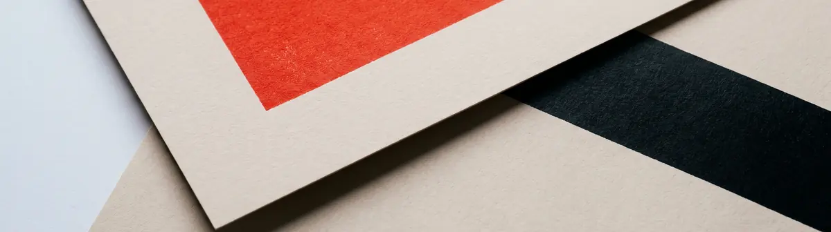 Dos hojas de papel solapadas, una con un cuadro de tinta roja y otra con una banda negra entrando por el borde.