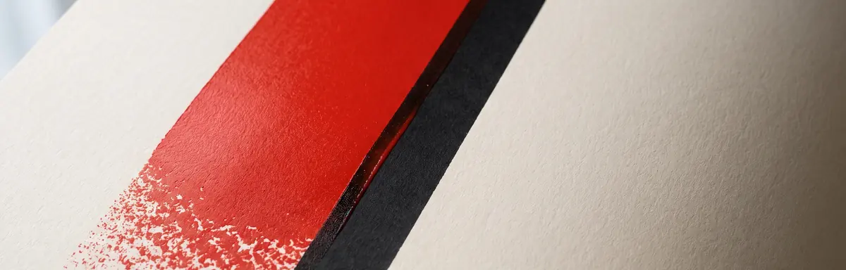 Dos bandas de tinta, una roja y otra negra, casi alineadas sobre una hoja de papel sin estucar.